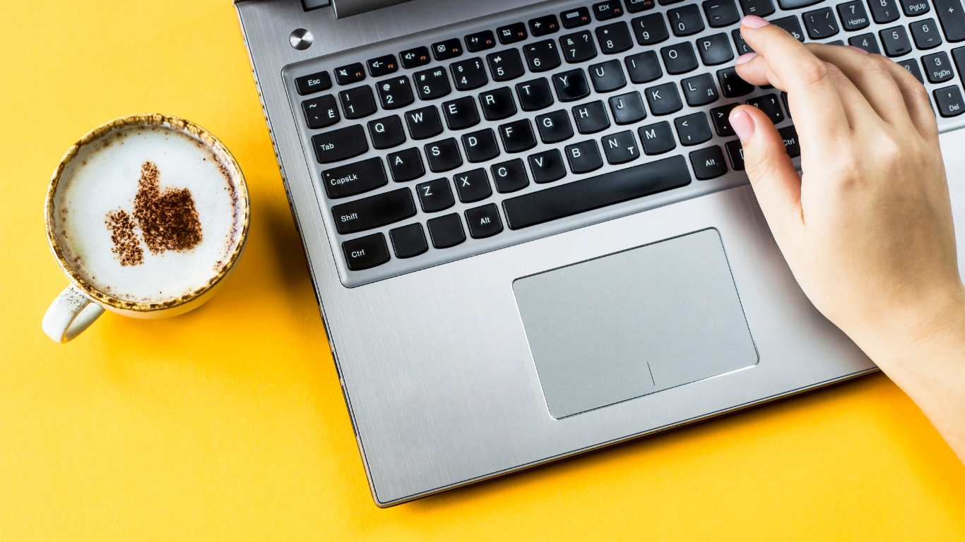 Typing-On-Laptop-Next-to-latte-with-thumbs-up-symbol